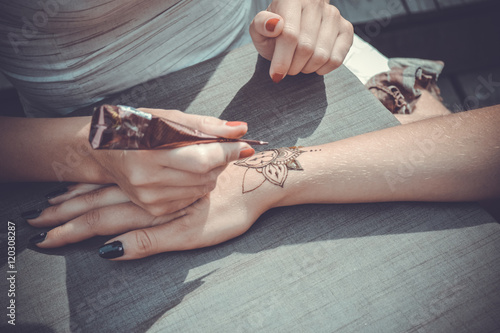 Master paints her hand with henna mehendi in styles photo
