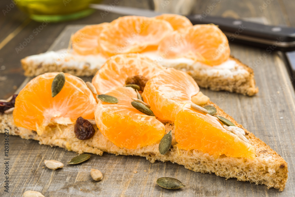 mandarin oranges and pine nuts on wholemeal bread spread with ch