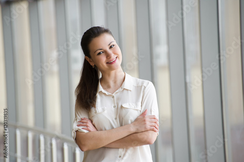 Young businesswoman standing by window in office. Free Download Young businesswoman standing by window in office. - GFXLoad