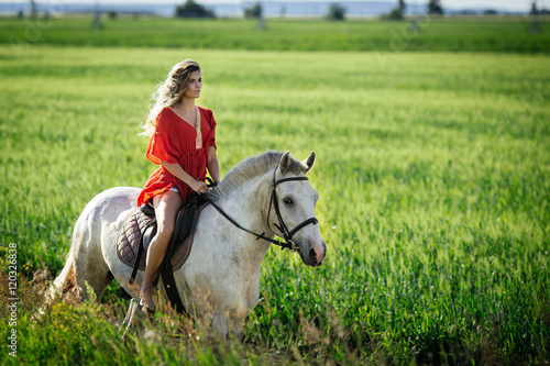 Beautiful blonde girl riding a horse in countryside