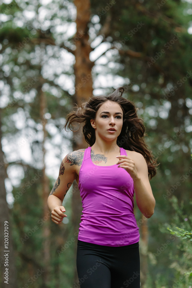 Young woman running in wood, training and exercising for trail run marathon endurance. Fitness healthy lifestyle concept.