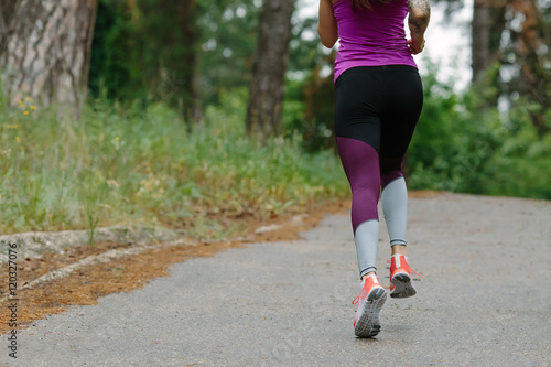Athlete runner feet running on road closeup on shoe. woman fitness jog workout wellness concept.