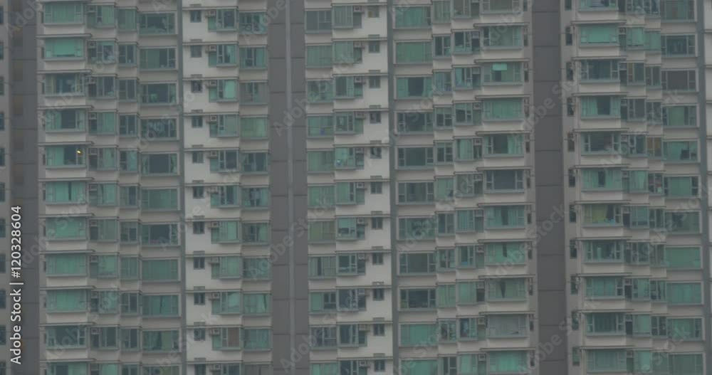Facade of high-rise apartment block with following view of huge crane working at construction site in Hong Kong Facade of high-rise apartment block with following view of huge crane working at construction site in Hong Kong