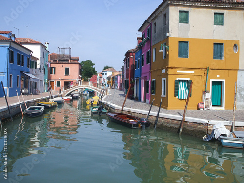 Canal in Burano, Italy. Burano is situated 7 kilometres (4 miles) from Venice. Burano is also known for its small, brightly painted houses, which are popular with artists