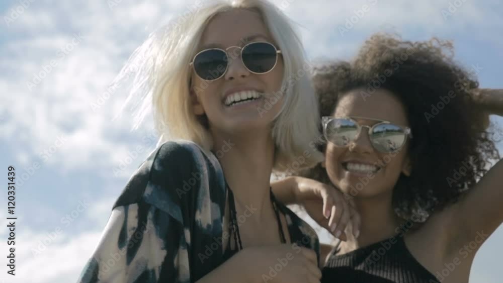 Two young happy hipster girls in sunglasses having fun, outdoor. Two pretty girlfriends smiling, laughing and fooling around during sunny day. Two young happy hipster girls in sunglasses having fun, outdoor. Two pretty girlfriends smiling, laughing and fooling around during sunny day.