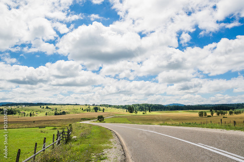 Asphalt road through the green field and clouds on blue sky  photo