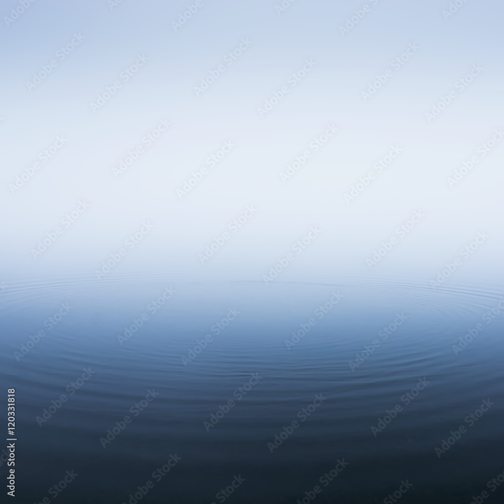 Thick morning fog on the lake. Circles on the water
