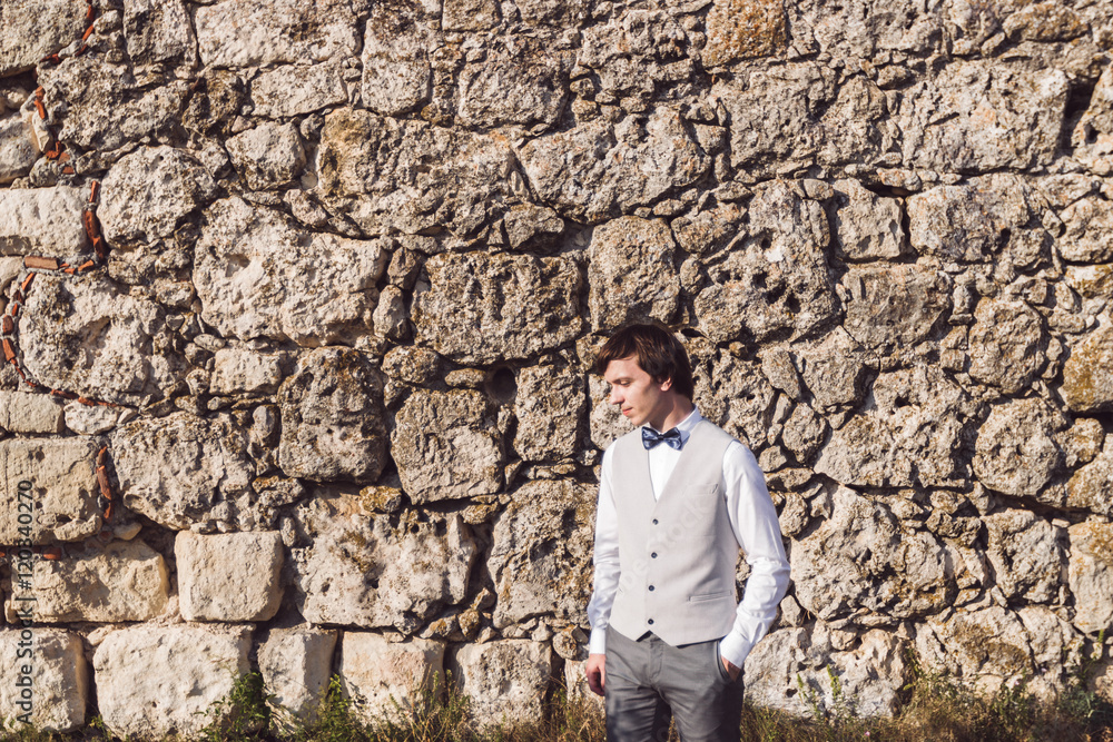 Groom potrait on stone background of the old fortress Groom potrait on stone background of the old fortress