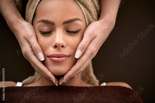 woman enjoying during facial massage in cosmetic salon