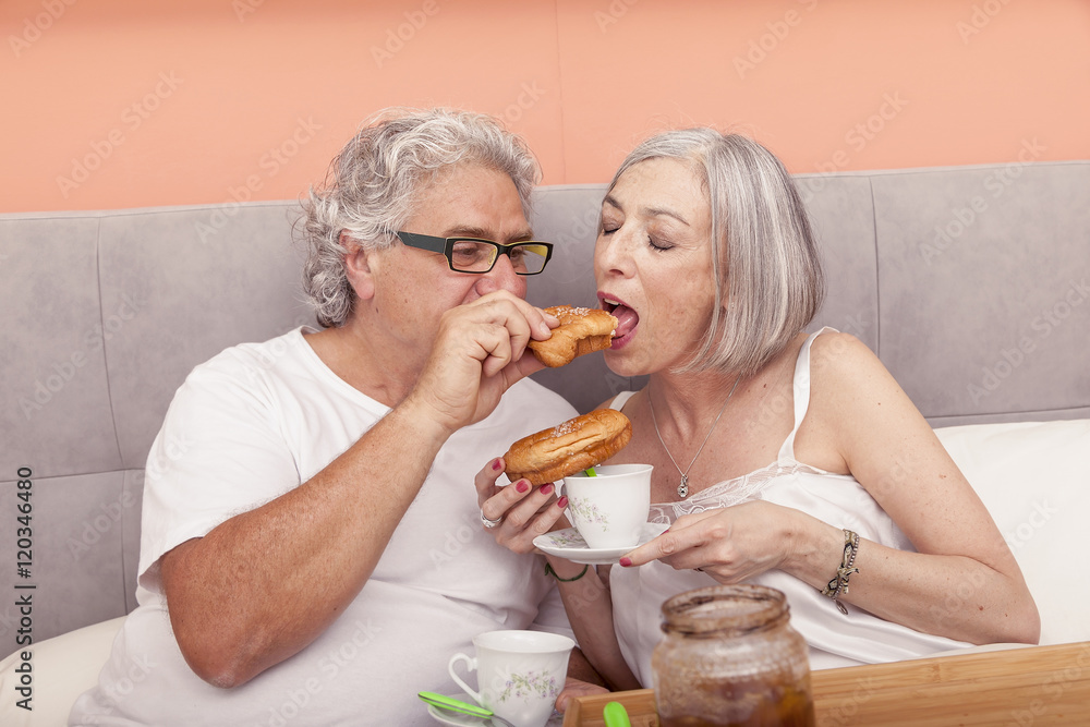 pretty mature couple having fun in the bed while eating breakfas pretty mature couple having fun in the bed while eating breakfas