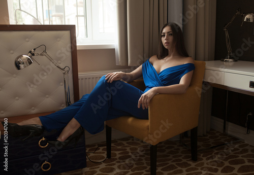 beautiful sexy woman wear long dark blue suit sit on armchair in interior furniture room © lashkhidzetim