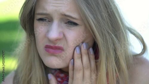 Pretty, blonde girl looking very unhappy because of toothache
