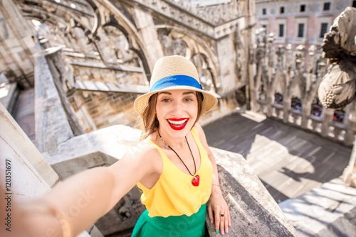 Young and happy female traveler making selfie portrait standing on the rooftop of the famous Duomo cathedral in Milan. Having great vacations in Milan © rh2010
