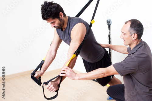 Personal trainer helping with suspension stretching exercise