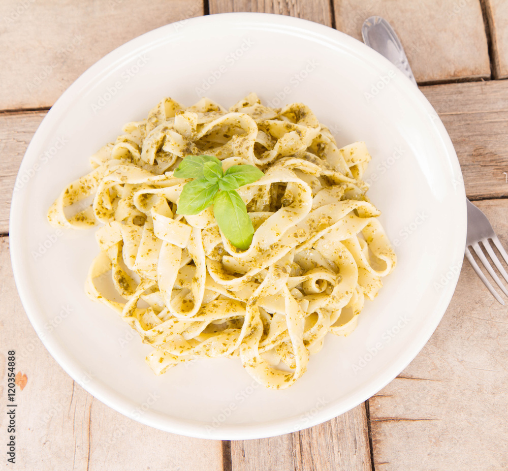 Tagliatelle with pesto decorated with basil on a wooden background