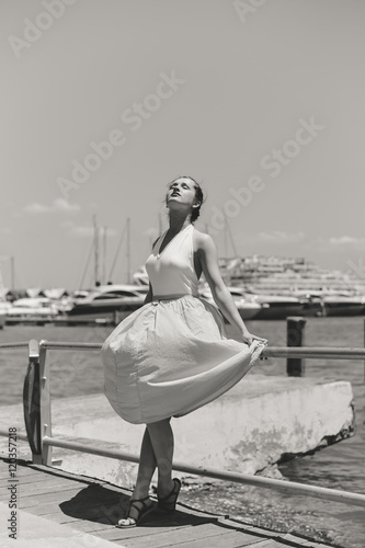 Black and white portrait of elegant beautiful young lady on marina pier sunny day outdoors background © gorosi