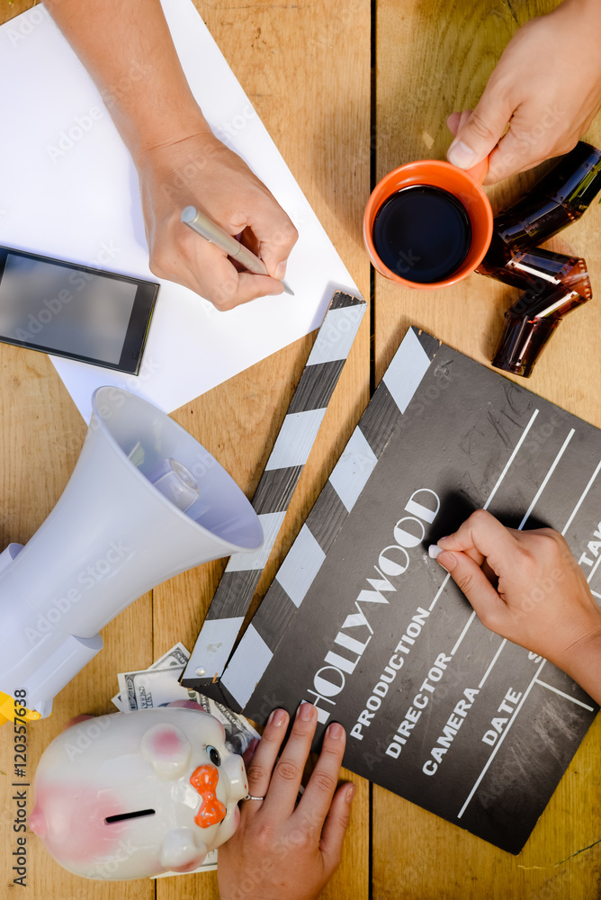 Fototapeta premium Film production process. Planning to make movie. Clapperboard, megaphone, piggy bank, mobile phone and alarm clock.