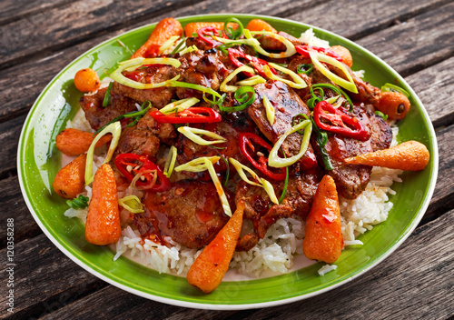 takeawy classic pork on rice with fried in sticky souce carrots, sprinkle of chillie and spring onion.