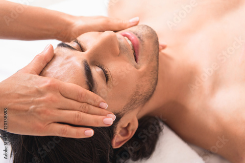 Happy man getting facial treatment at massaging center