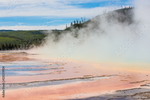 Rising blue steam and mist from Grand Prismatic hot spring in Midway Geyser basin at Yellowstone National Park with red bacterial patterns