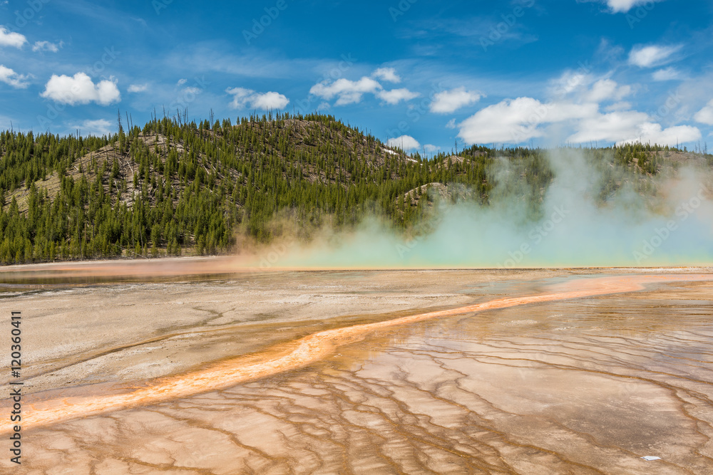 Rising blue steam and mist from Grand Prismatic hot spring in Midway Geyser basin at Yellowstone National Park with red bacterial patterns