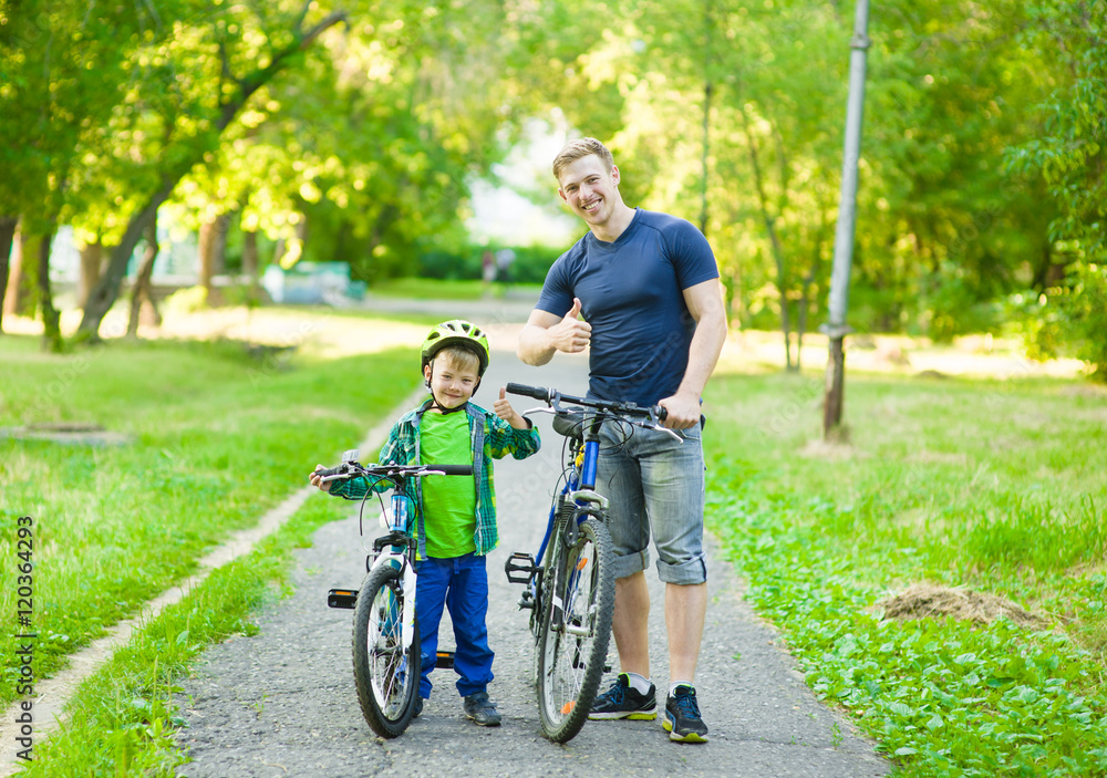 portrait of a happy family - father and son bicycling in the park