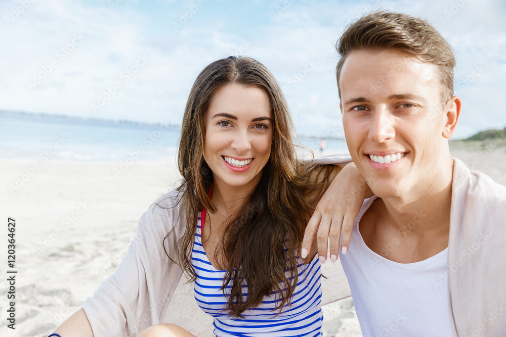 Obraz premium Romantic young couple sitting on the beach
