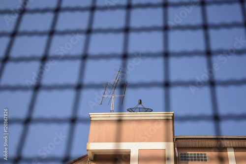 Buildings with satellite dishes on top. Behind the wire mesh