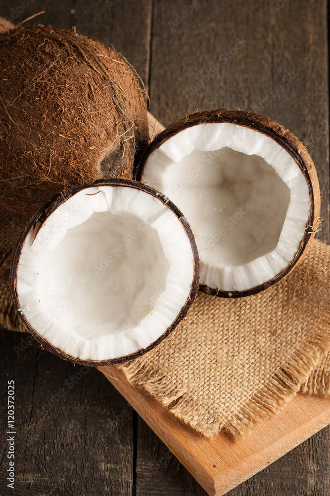Ripe half cut coconut with milk on a wooden background