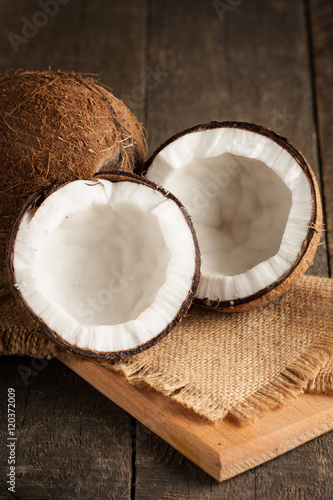 Ripe half cut coconut with milk on a wooden background