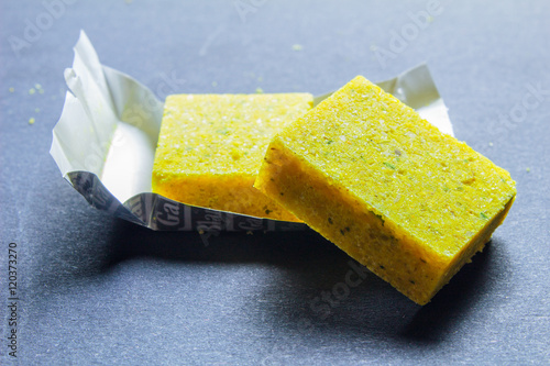 Dehydrated bouillon stock cube salty meat and vegetables aromatic yellow spice, ingredient single whole condiment portion wrapped, open in paper pack