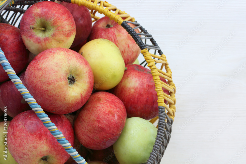 harvest fresh fruit/ many apples in a rustic wicker basket on a light wooden background harvest fresh fruit/ many apples in a rustic wicker basket on a light wooden background
