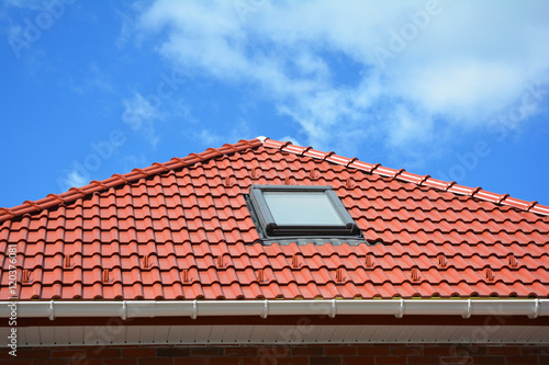 Skylight on red ceramic tiles house roof with rain gutter. Skylights, Roof Windows and Sun Tunnels. Attic skylight solution outdoor.