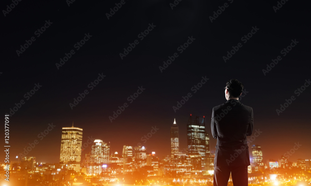 Businessman viewing night glowing city Businessman viewing night glowing city