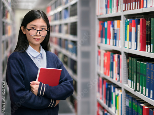 Junge Studentin mit Buch in der Bibliothek photo