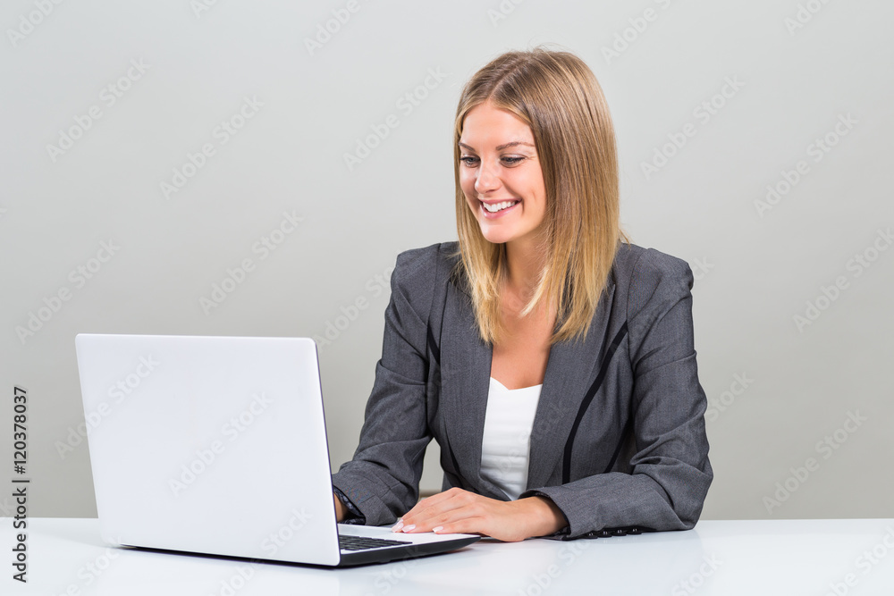 Beautiful businesswoman is sitting at the table and using laptop.
Beautiful businesswoman is sitting at the table and using laptop.