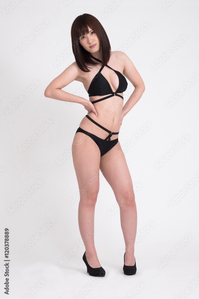 黒色のビキニを着た女性モデルが、ポーズをして立っています。 黒色のビキニを着た女性モデルが、ポーズをして立っています。