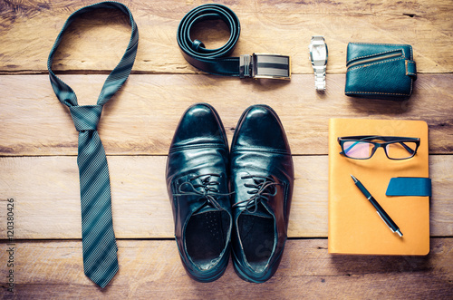 Leather shoes and accessories for work lay on the wooden floor