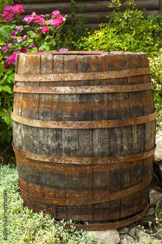old wooden barrel amid garden pink flowers