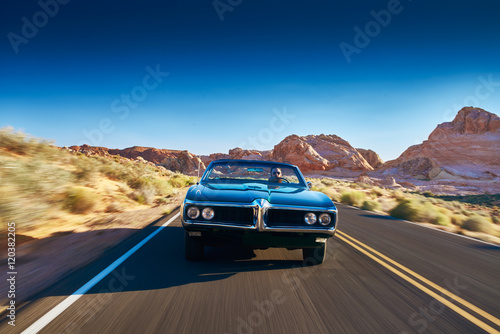 man driving vintage car through desert