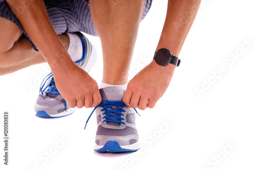 Lifestyle, sport and technology. Close up of male hands with smartwatch tying sneakers. Isolated on white.