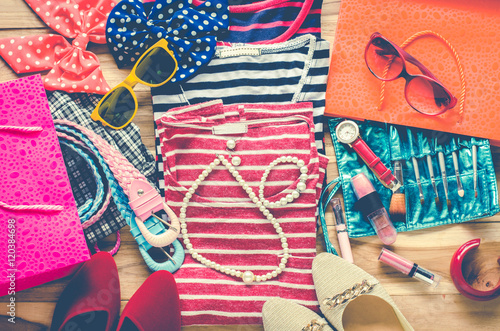 Colorful clothes and accessories to dress arranged on a wooden table.