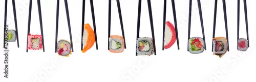 Obraz  z motywem A lot of sushi and rolls in black chopsticks isolated on white background