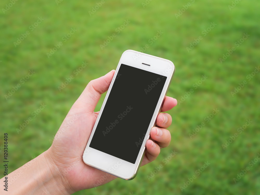 Human hand holding mobile phone against blurred green field background, Horizonta