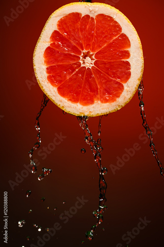 Fresh water drops on grapefruit at red background