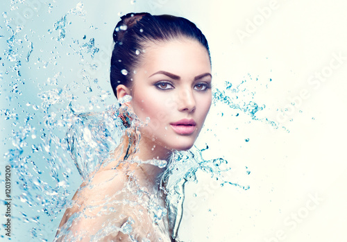 Beauty spa woman under splash of water over blue background