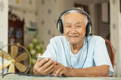 Happy asian senior man Headphones Listening Music at home