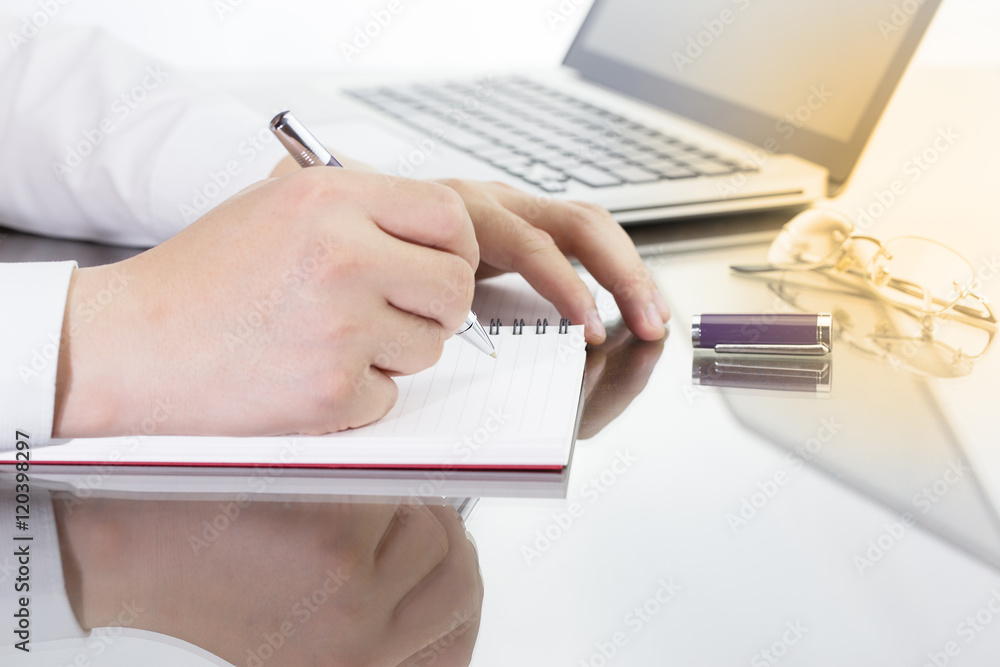 Businessman write a short note on opened notebook with pen and glasses. Businessman write a short note on opened notebook with pen and glasses.