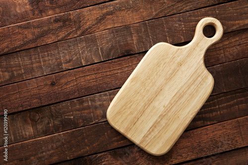 Cutting board on a wooden table, top view