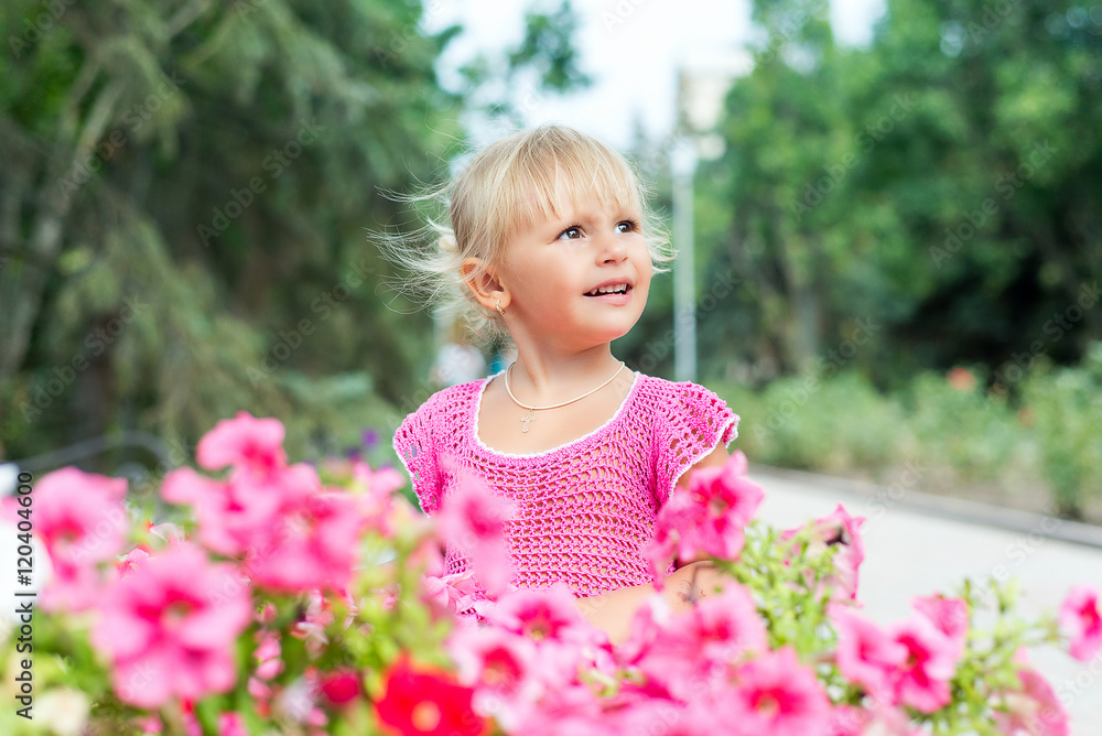 The child, a little girl is smelling the blooming petunias. The child, a little girl is smelling the blooming petunias.